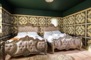 2 camas en un dormitorio con papel pintado ornamentado en Cinema & Games Room Pool Table, Hot Tub, Sleeps 15, en Saffron Walden