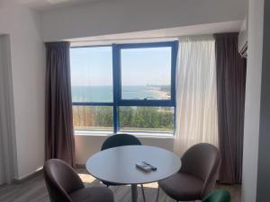 a room with a table and chairs and a large window at Sea View Apartments Olimp Etajul 9 in Olimp