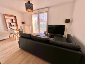 a living room with a black couch and a television at Cosy Cocoon Campagne in Vert-le-Grand