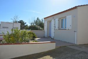 un bâtiment blanc avec une porte et une clôture dans l'établissement Maison avec 2 terrasses à 400 mètres de la plage, au Barcarès