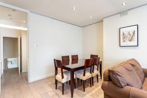 a dining room with a table and chairs and a couch at Cosy Kensington Two Bedroom Flat in London