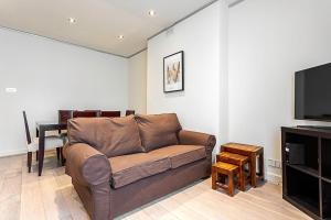 a living room with a couch and a flat screen tv at Cosy Kensington Two Bedroom Flat in London