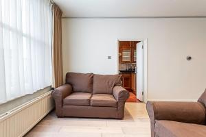 ein Wohnzimmer mit einem Sofa und einem Stuhl in der Unterkunft Cosy Kensington Two Bedroom Flat in London