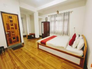 1 dormitorio con 1 cama y suelo de madera en Jain Homestay, en Darjeeling