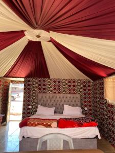a bed in a room with a large ceiling at Desert guide camp in Wadi Rum