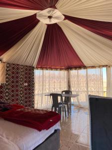 una camera da letto con tenda, tavolo e sedie di Desert guide camp a Wadi Rum