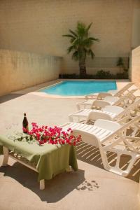 a pool with white chairs and a table with flowers on it at Casa Sammy in Sannat