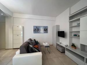 uma sala de estar branca com um sofá e uma televisão em Appartamento BN1 em Follonica