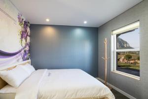 a bedroom with a large bed with a blue wall at Monteview Stay in Seogwipo