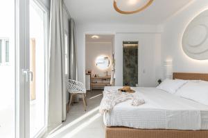 a white bedroom with a bed and a chair at Golden Bird's in Naxos Chora