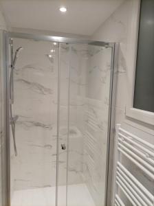 La salle de bains est pourvue d'une douche en marbre blanc. dans l'établissement Versailles Direct : T2 Authentique et Chaleureux, à Versailles