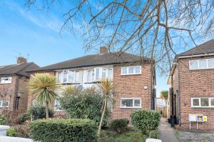 uma casa de tijolos com janelas brancas e arbustos em Sunny 2BD London Maisonette with Garden for 3 em Londres