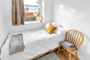 Cama en habitación con ventana y silla en Sunny 2BD London Maisonette with Garden for 3, en Londres