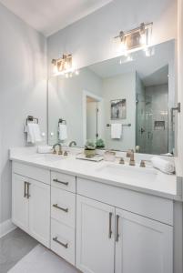 a white bathroom with two sinks and a large mirror at Noble Nash - 8 Mins to Grand Ole Opry in Nashville