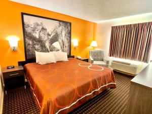 a hotel room with a bed with an orange bedspread at Super 8 by Wyndham Hillsville in Hillsville