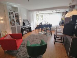 ein Wohnzimmer mit roten und grünen Stühlen und einem Klavier in der Unterkunft Lovely central flat with grand piano, family friendly in Berlin