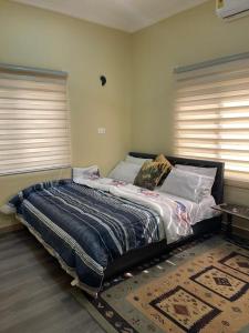 Bett in einem Zimmer mit zwei Fenstern in der Unterkunft SKY Havens Apartments in Accra