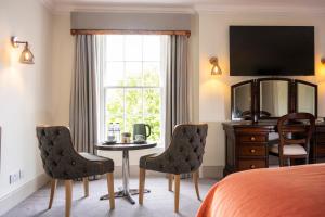 a hotel room with a bed and a table and chairs at Knipoch House Hotel in Oban