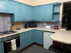 a blue kitchen with white appliances and blue cabinets at 18 Main Street in St Bees