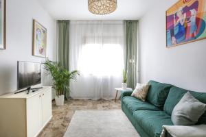 a living room with a green couch and a television at Peggy's House in Venice