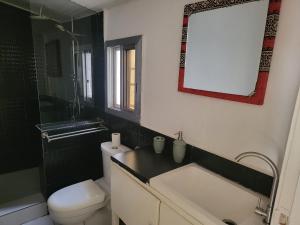 a bathroom with a toilet and a sink and a mirror at Cozy 2 Bedroom Bungalow. in Freetown +14 photos