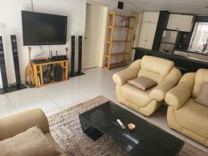 a living room with two couches and a tv at Cozy 2 Bedroom Bungalow. in Freetown
