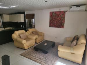 a living room with two couches and a table at Cozy 2 Bedroom Bungalow. in Freetown