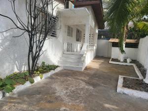 a white building with stairs and a palm tree at Cozy 2 Bedroom Bungalow. in Freetown