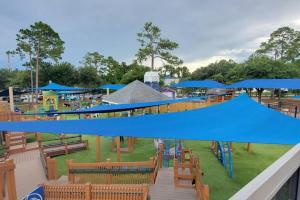 a park with a playground with blue umbrellas and benches at Fun 5* Hot Tub/Beaches getaway Near MAYO in Jacksonville