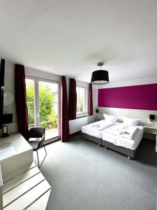 1 dormitorio con 2 camas y pared púrpura en Hotel Brinckmansdorf, en Rostock
