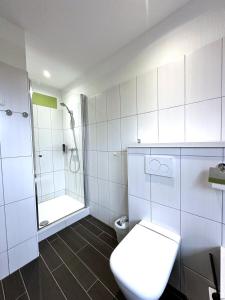 a white bathroom with a toilet and a shower at Hotel Brinckmansdorf in Rostock