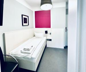 a room with a white bed and a pink wall at Hotel Brinckmansdorf in Rostock