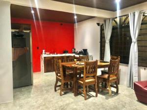 eine Küche mit einem Tisch, Stühlen und einer roten Wand in der Unterkunft Casa las pavas Bijagüa in Bijagua