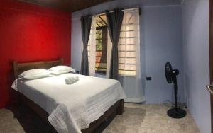 ein Schlafzimmer mit einem Bett mit einer roten Wand und einem Fenster in der Unterkunft Casa las pavas Bijagüa in Bijagua