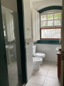 uma casa de banho com WC, 2 lavatórios e uma janela em CASA EM PARATY - EXCELENTE LOCALIZAÇÃO em Paraty
