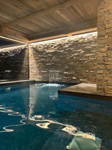 an indoor swimming pool with a stone wall at LA CABANE DU BREUIL in La Bresse