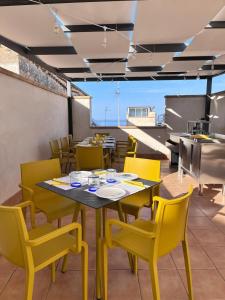 a dining room with a table and yellow chairs at Colibri B&B in Sciacca