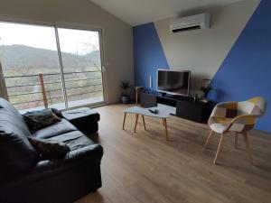 ein Wohnzimmer mit einem Sofa und einem TV in der Unterkunft Maison vigneronne climatisée in Polignac