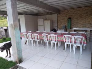 eine Reihe von Tischen und Stühlen mit einem Hund auf einer Terrasse in der Unterkunft Recanto do cowboy in Vila Velha