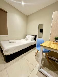 um quarto com uma cama, uma mesa e uma cadeira azul em Swing & Pillows PJ Sunway Mentari formerly known as Swan Cottage Hotel em Petaling Jaya