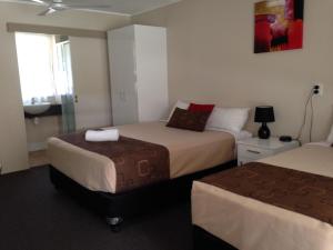 a hotel room with two beds and a sink at Kalua Motel in Bundaberg