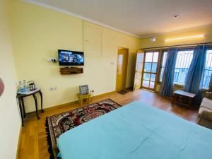 Cette chambre comprend un lit et une télévision murale. dans l'établissement Kumaon Hills view Homestay, à Mukteswar