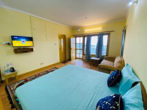 Un dormitorio con una cama azul y un televisor. en Sunstone House, en Mukteshwar