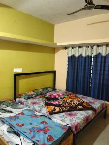 een slaapkamer met een bed en een raam met blauwe gordijnen bij Coorg Orange Villa in Madikeri