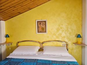 - une chambre dotée d'un lit avec un mur jaune dans l'établissement Mansarda Natalie, à Levanto