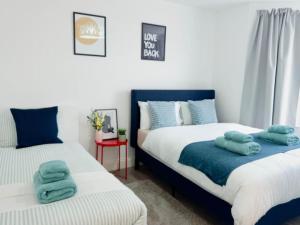 2 Betten in einem Schlafzimmer mit blauen Handtüchern darauf in der Unterkunft Spacious 1-Bed Flat Near Wembley Stadium in London