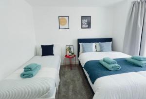 2 Betten in einem Zimmer mit blauen Handtüchern darauf in der Unterkunft Spacious 1-Bed Flat Near Wembley Stadium in London