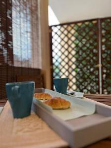 una bandeja de comida sentada en una mesa con dos tazas en Tasinanta casa vacanze, en Santa Luria