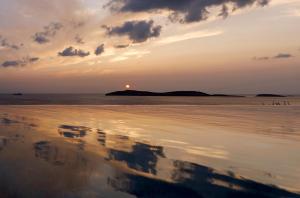 a sunset on the beach with a reflection in the water at Villa Gaia, Beachfront, Plunge Pool & Sunset by Explore Andros in Apróvaton
