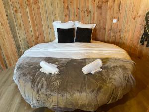 Cama en habitación de madera con 2 almohadas en La Cabane Tonneau - Les Pieds dans le Pré, en Les Landes-Génusson